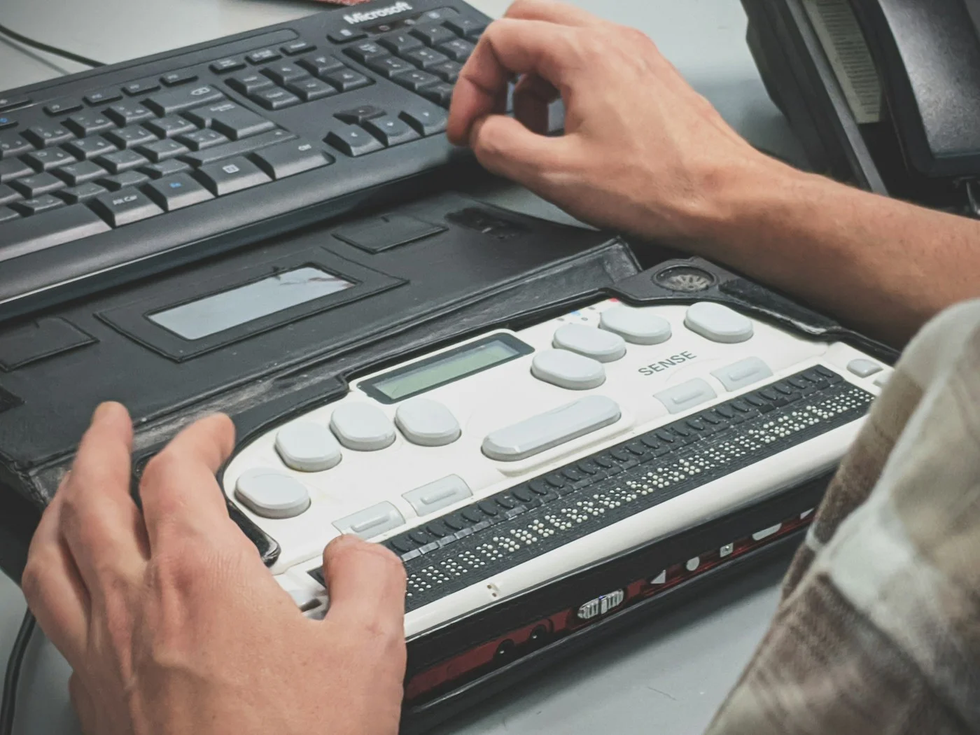 Iemand gebruikt een brailleleesregel bij een toetsenbord